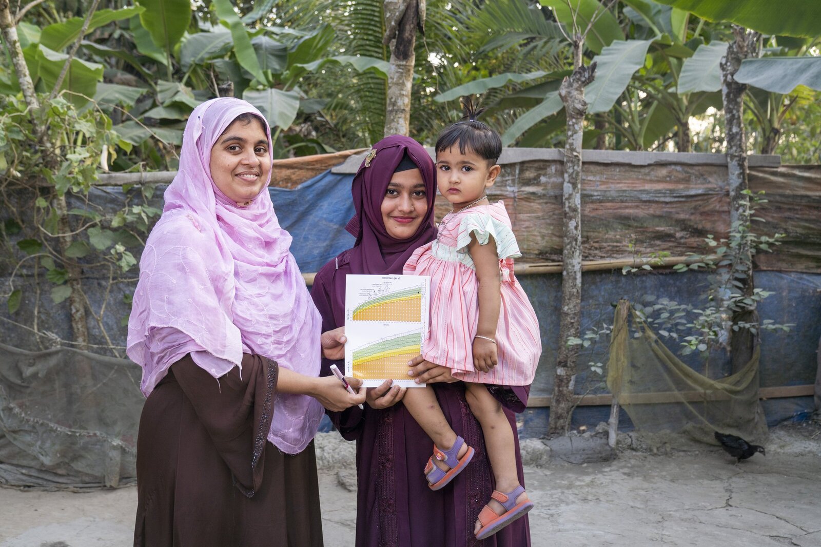 A Healthy Village entrepreneur and a mother review a child's growth chart together during a home visit in Barishal, Bangladesh.
